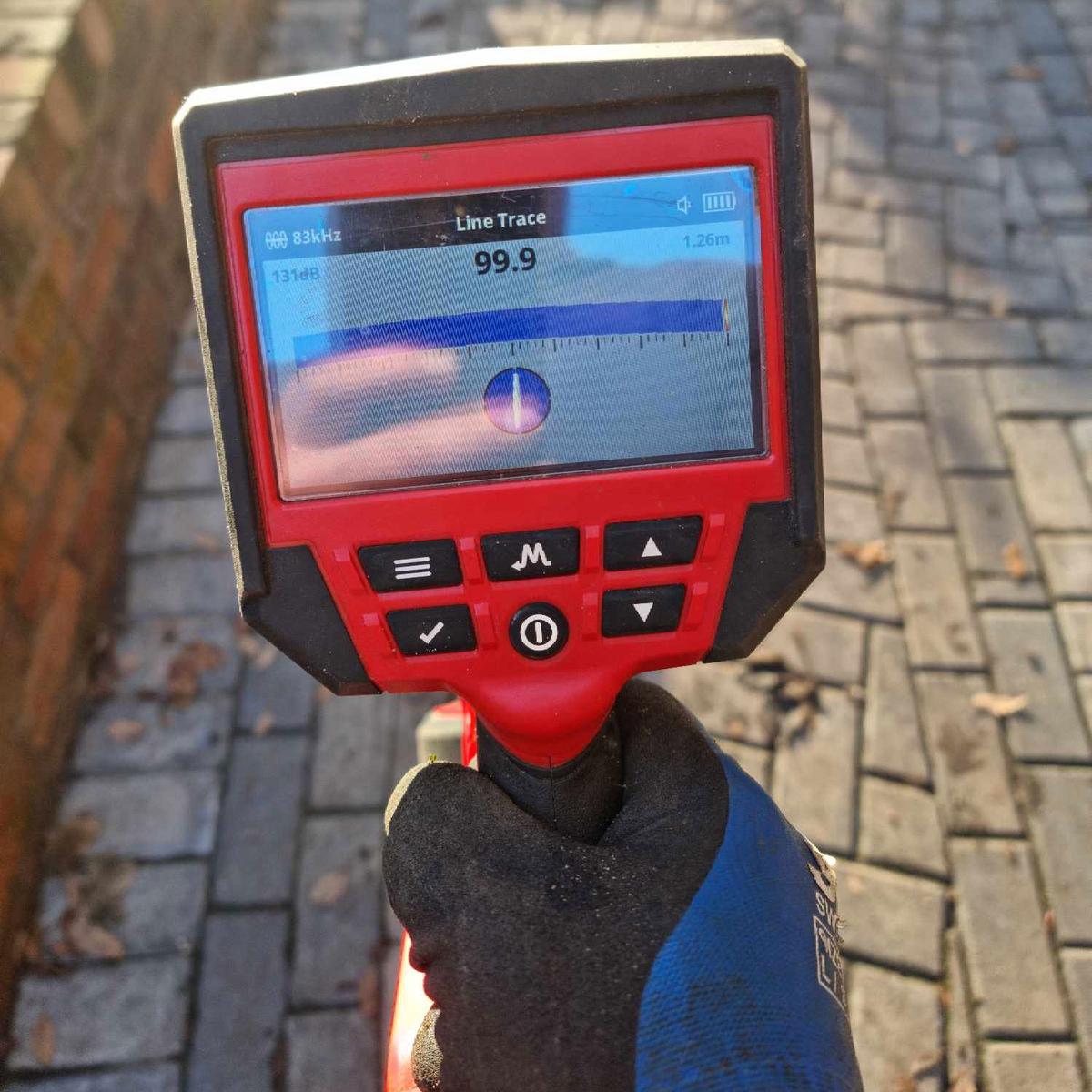 A photo of a drainage engineer conducting a drainage system survey with a line trace tool.
