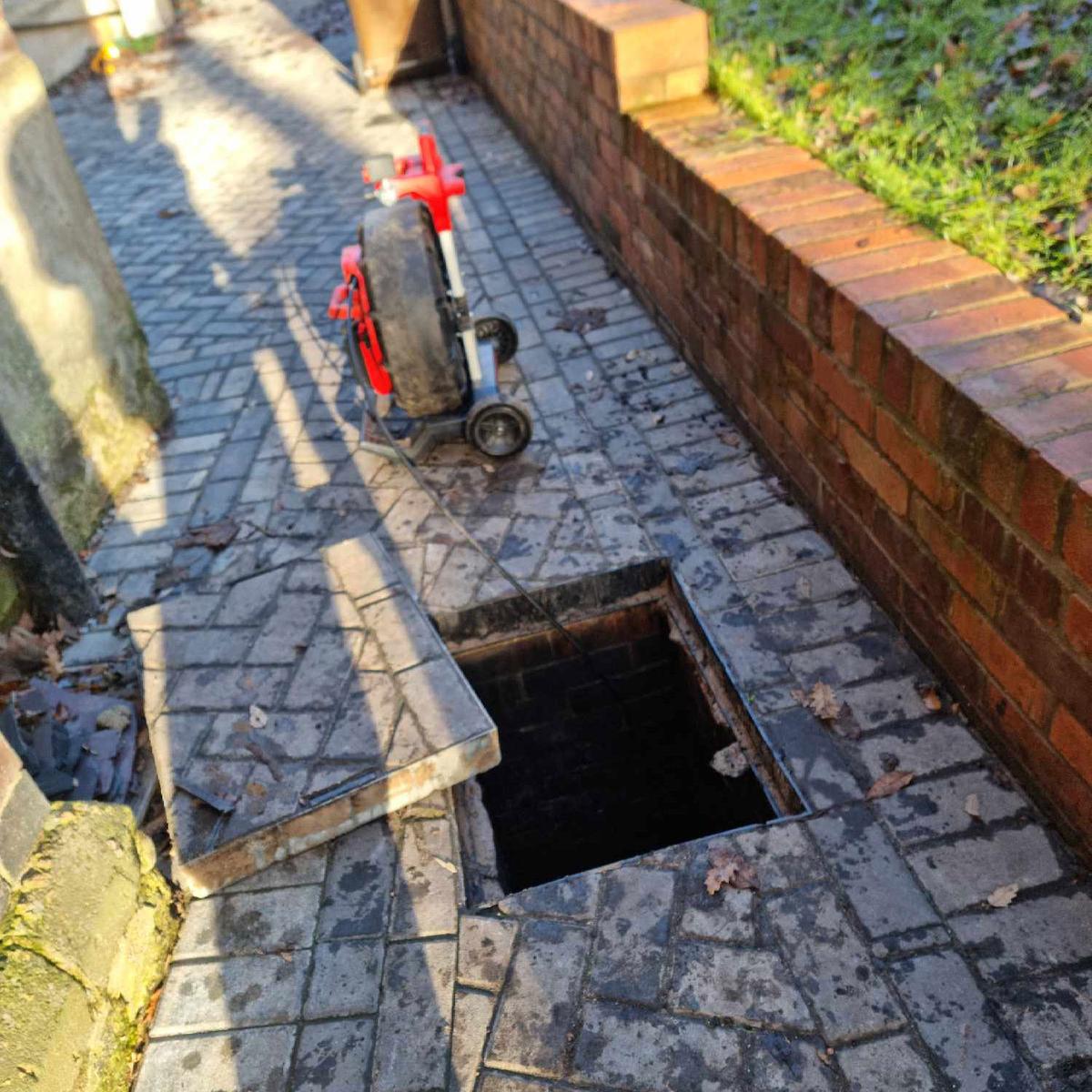 A photo of a drainage engineer using a locator tool to find and unblock a drain.