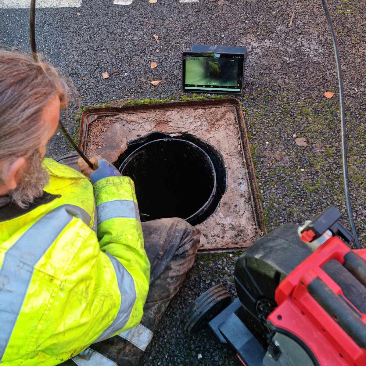A drainage engineer using a CCTV inspection tool on a drainage system for a drain survey