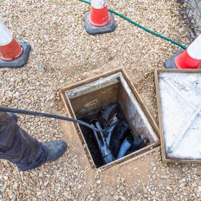 A drainage engineer using a high pressure jetter to unblock a manhole.