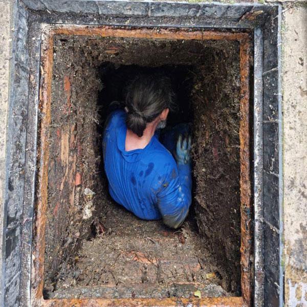 A photo of a drainage engineer inspecting a drain for a drain survey