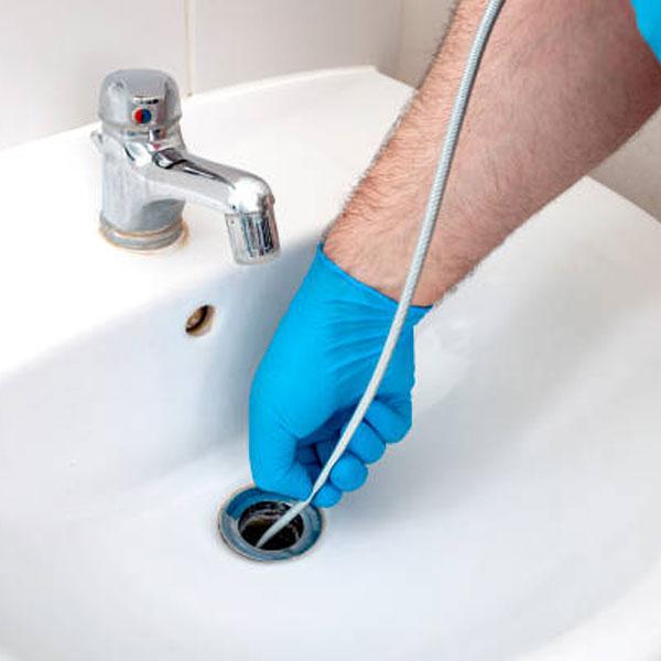 a photo of a drainage engineer unblocking a sink with a jetter